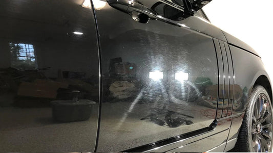 Side view of a black car with reflective surface showing indoor setting